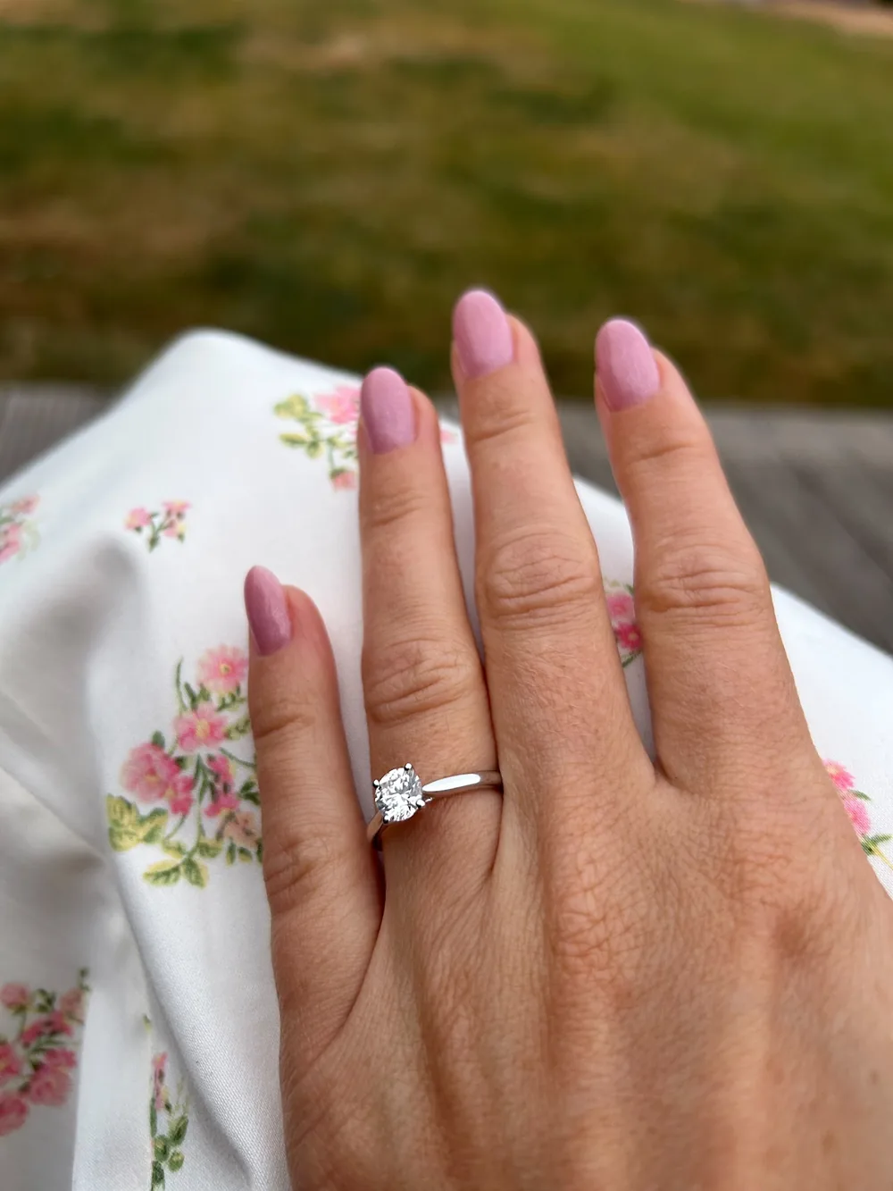 Hand met roze nagels en een verlovingsring
